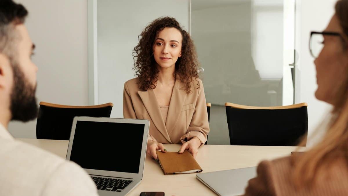 A woman in a business suit participates in a job interview, showcasing professionalism and modern office environment.