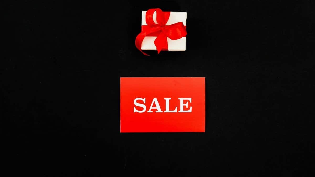 Top view of a red sale card and gift box with a ribbon on a black background. Perfect for shopping promotions.