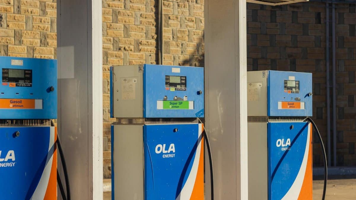 Three blue OLA Energy gas pumps at an outdoor station on a sunny day.