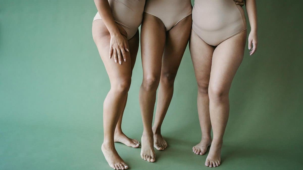 Three women in beige swimsuits showcasing body positivity and diversity on a green background.