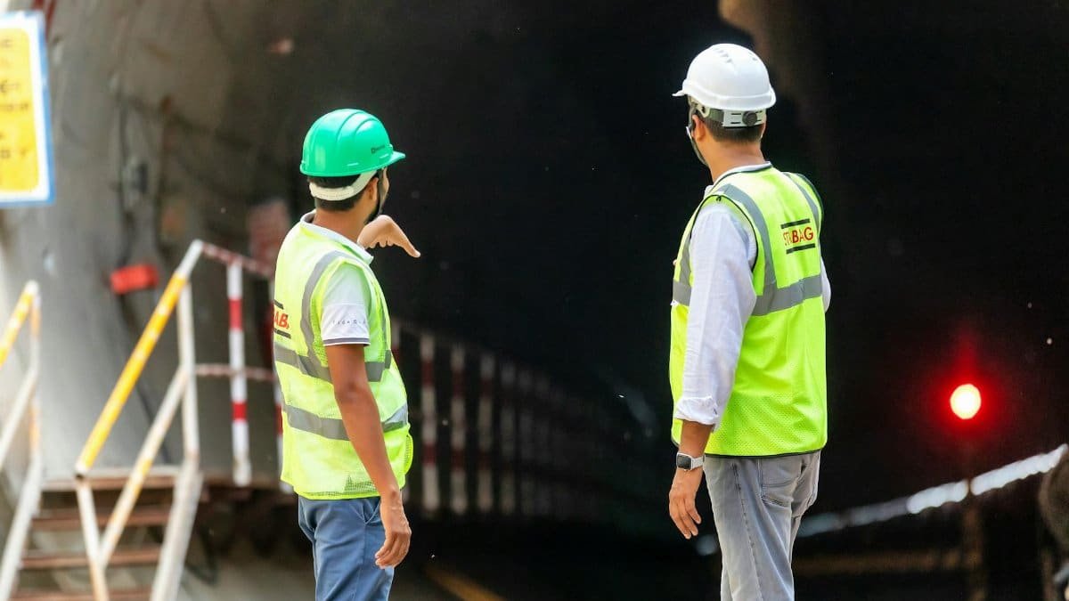 Two construction workers examine a tunnel entrance, highlighting safety and teamwork in infrastructure projects.