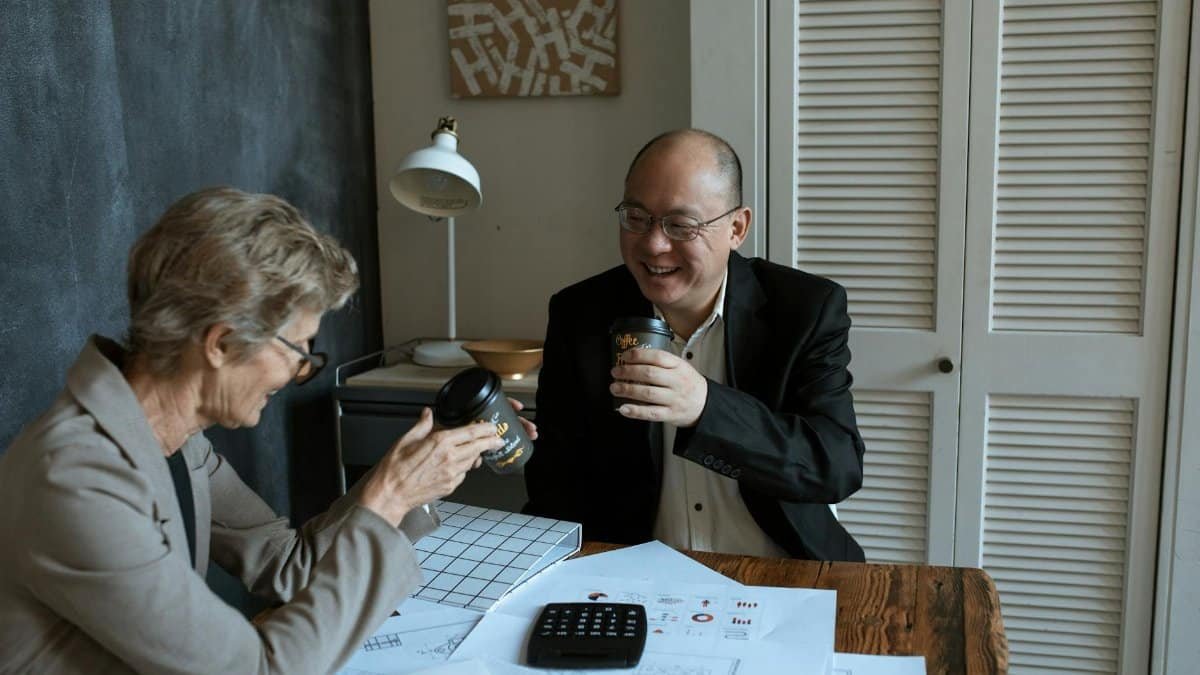 Business professionals sharing coffee and charts at an office table.