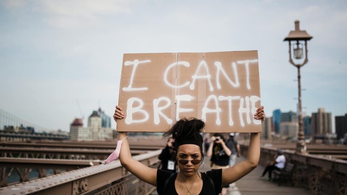 A protester holds an 'I Can't Breathe' sign during a demonstration on a bridge.