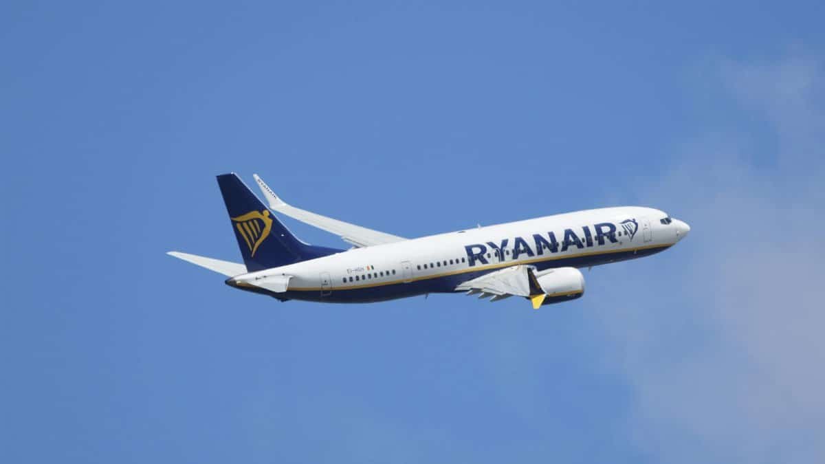 A Ryanair airplane captured in flight against a clear blue sky, showcasing modern air travel.