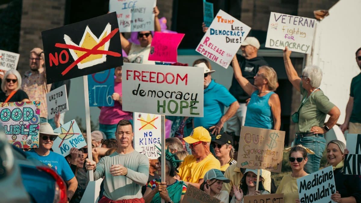 A diverse group of protesters holds signs advocating for freedom and democracy at a daytime rally.