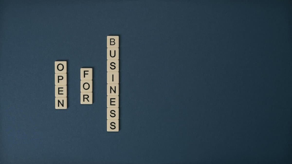 Scrabble tiles spelling 'Open for Business' on a blue backdrop with copyspace.