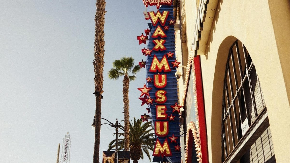 Hollywood Wax Museum sign with palm trees on sunny day, iconic Los Angeles location.