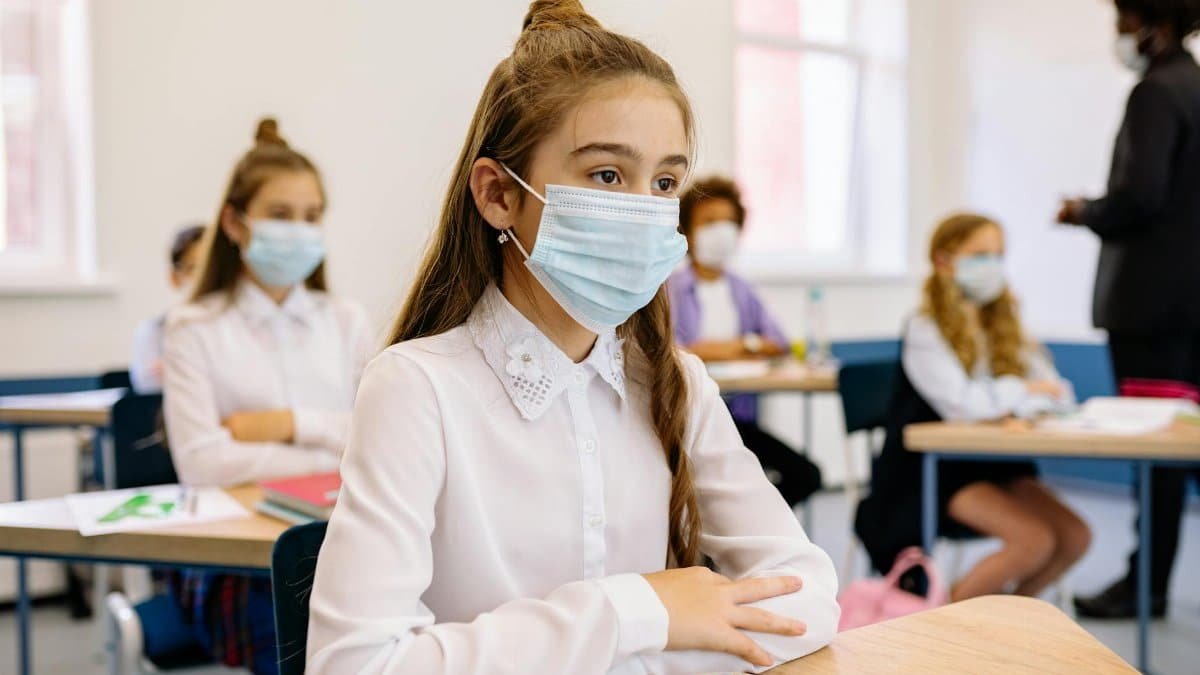 Students wearing face masks in a classroom during lessons for safety.