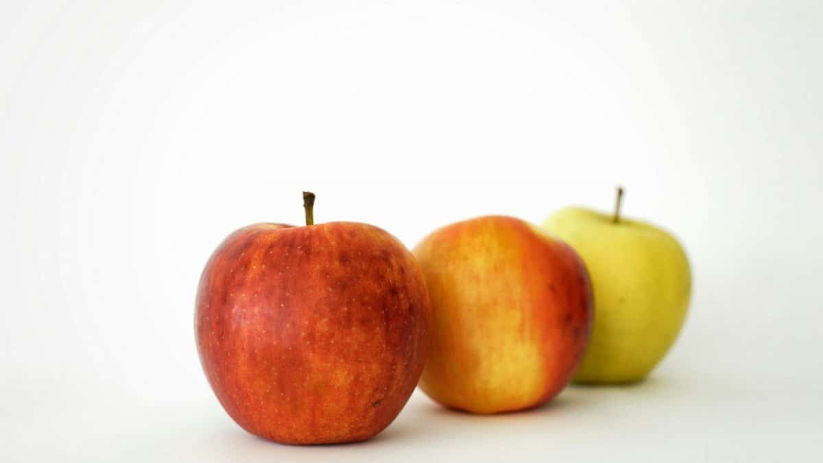 Three crisp apples in different colors against a white backdrop, showcasing fresh and healthy fruit.