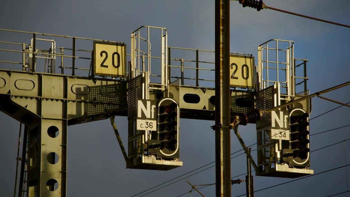 A close-up view of an industrial train signal with lit indicators during dusk, showcasing infrastructure details.