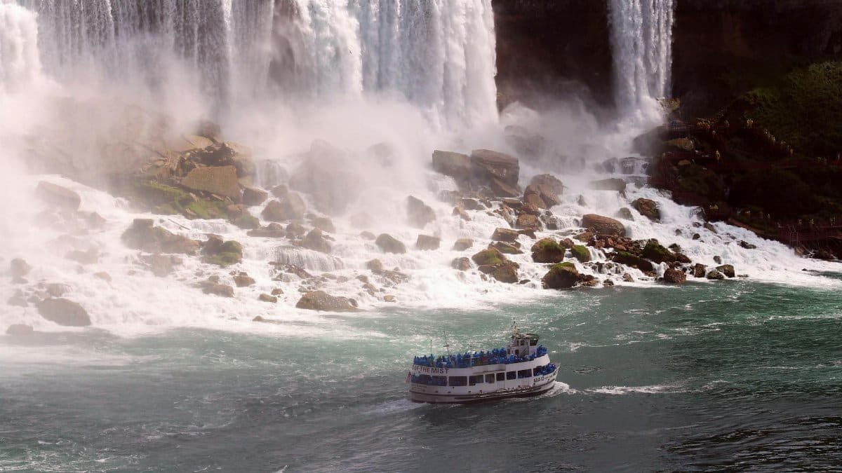 A breathtaking view of Niagara Falls with a ferry boat navigating the misty waters below.