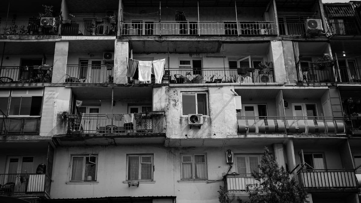 Monochrome view of an old apartment building with balconies and laundry hanging out.