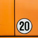 Close-up of a vintage orange vehicle door featuring a bold number 20 in a circle.