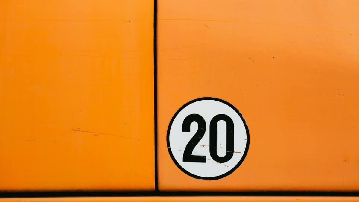 Close-up of a vintage orange vehicle door featuring a bold number 20 in a circle.