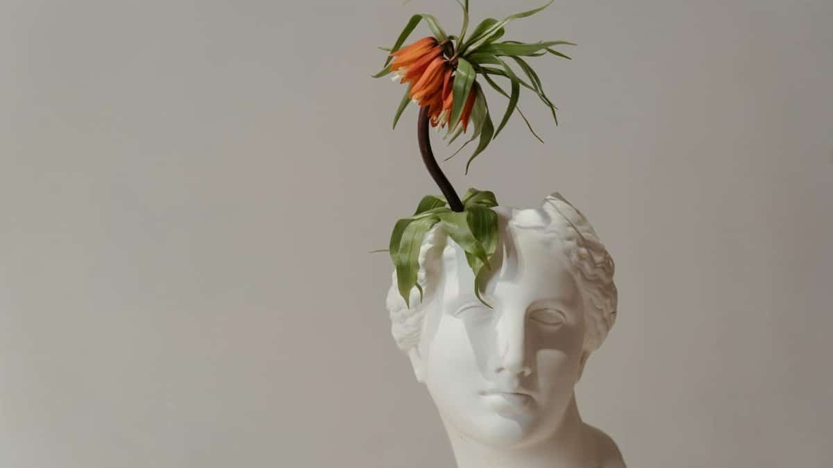 Artistic bust with an orange flower arrangement, blending classic and modern art styles.