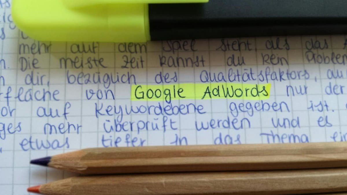 Close-up of colorful pencils on handwritten notes with Google AdWords highlighted.
