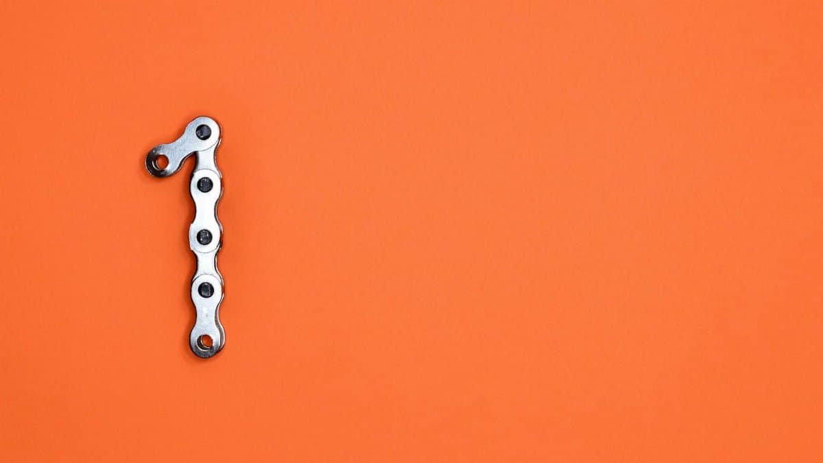 Metal chain forming the number one on an orange background, ideal for design concepts.