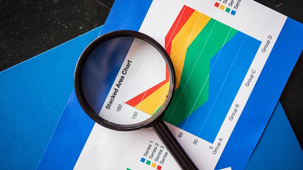 Magnifying glass highlighting stacked area charts for business analysis.