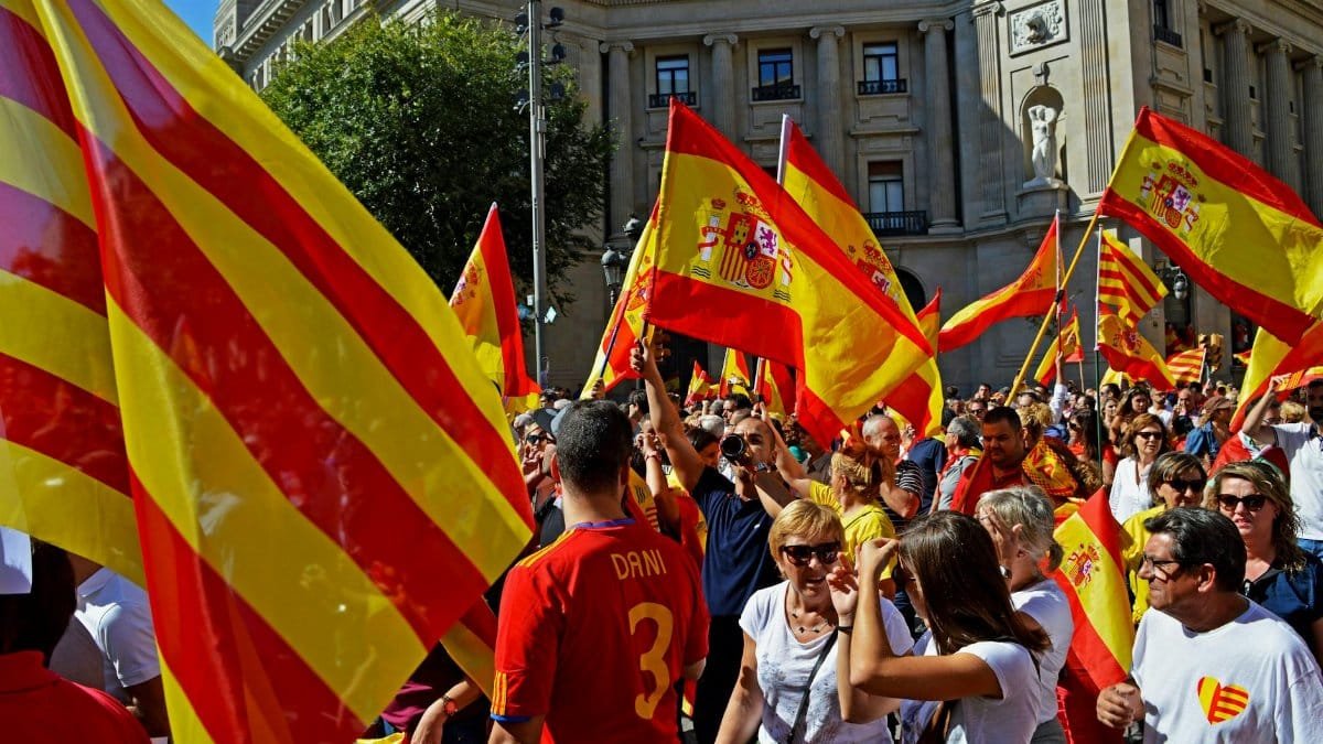 Colorful rally in Barcelona featuring Catalan and Spanish flags and a lively crowd.