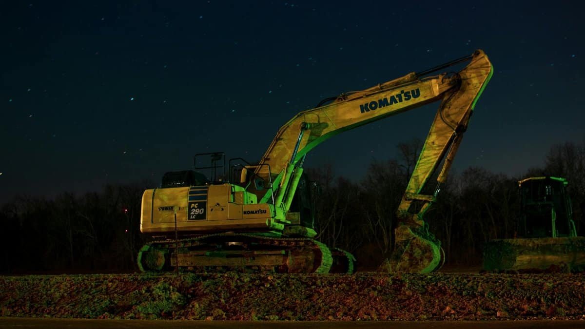 A Komatsu excavator at night, highlighting its silhouette against a starry sky.