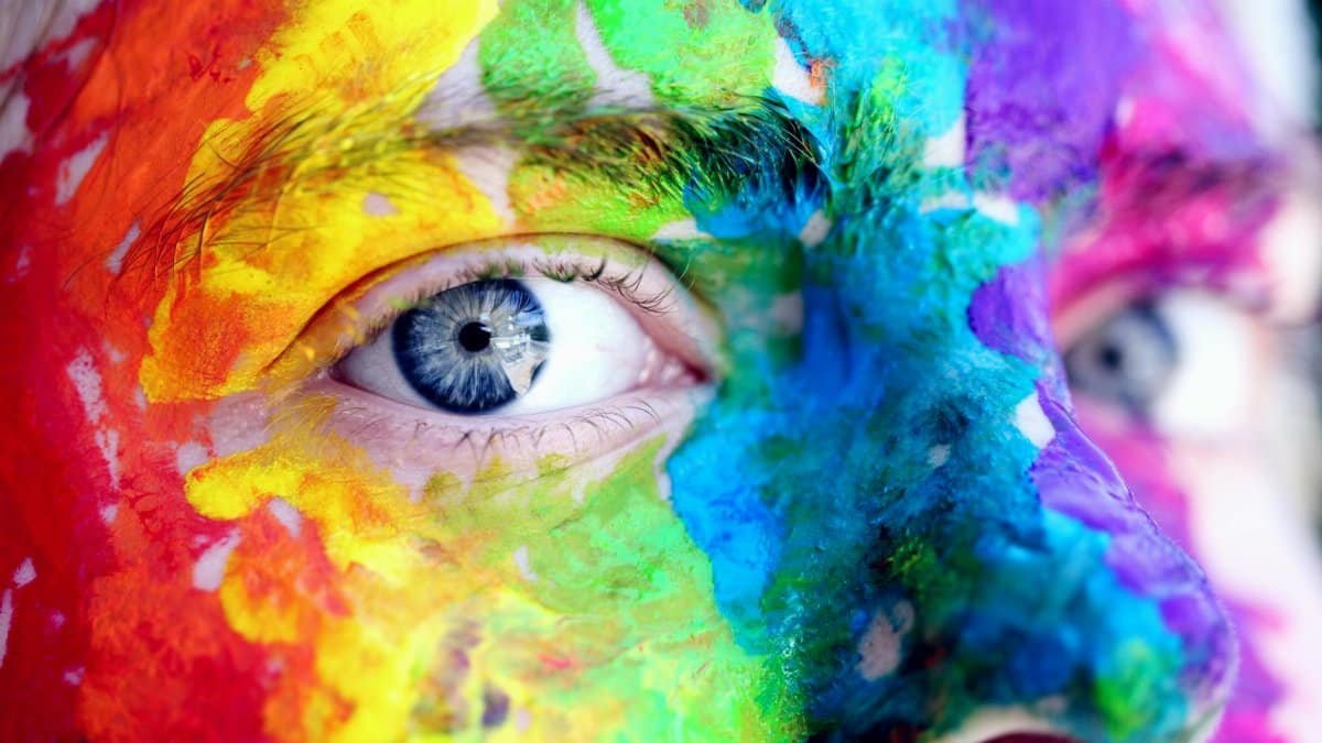 Close-up of a person with colorful rainbow face paint, symbolizing LGBT pride and expression.