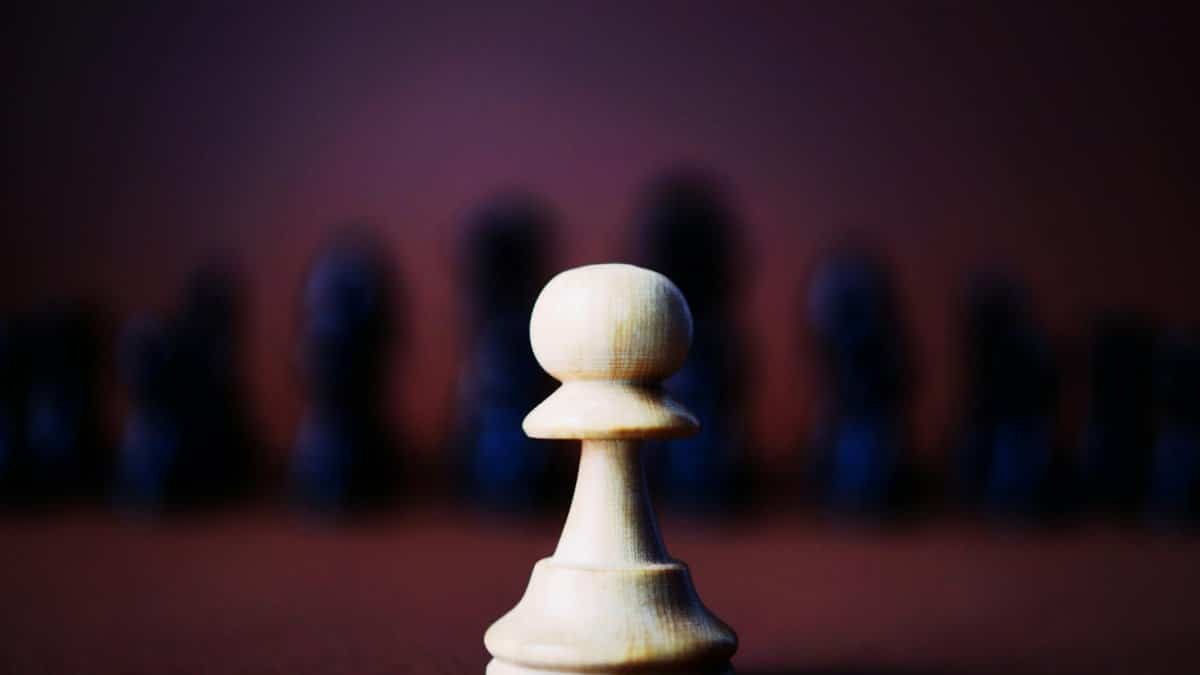 A detailed close-up of a wooden chess pawn against a blurred background, representing strategy.