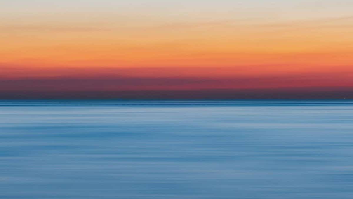 A colorful sunset over a calm ocean, perfect for vibrant backgrounds.