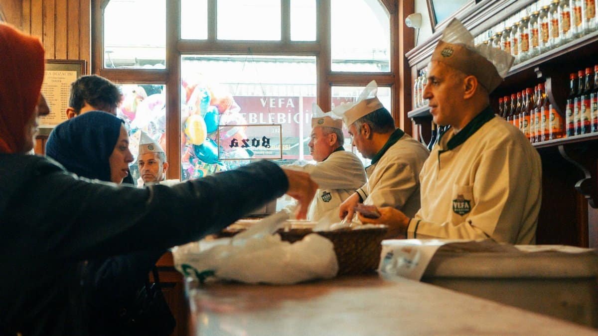 People interacting in a classic Turkish sweet shop with chefs serving.