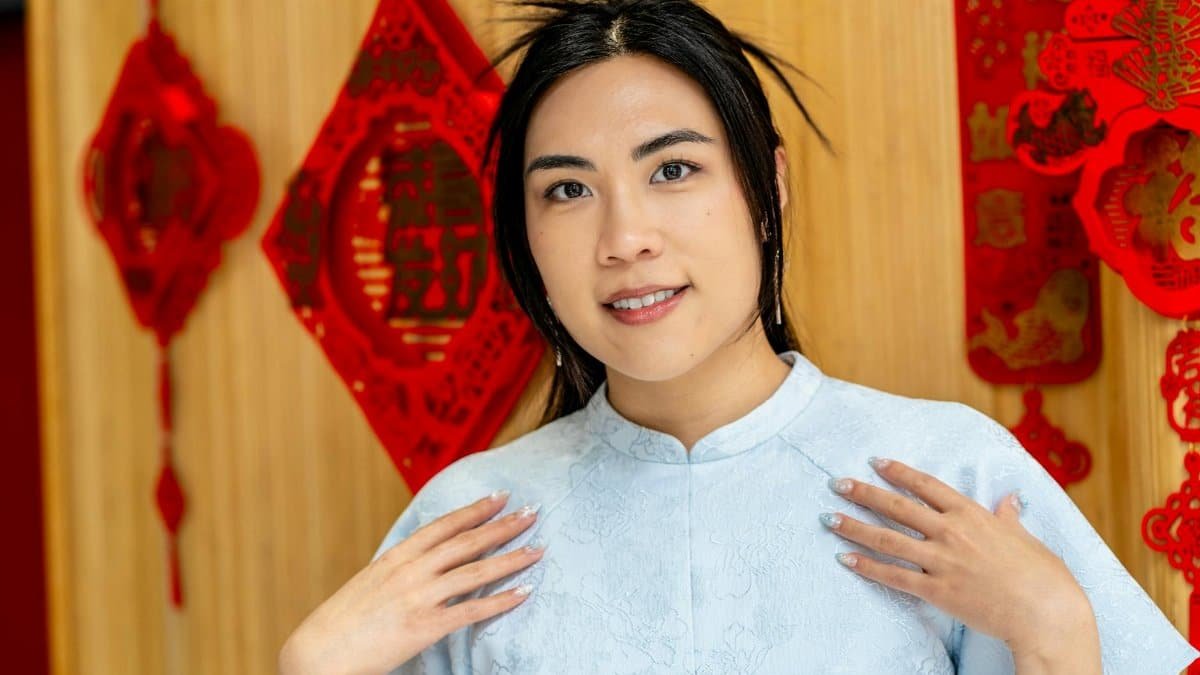 Elegant portrait of an Asian woman in blue traditional dress, celebrating Lunar New Year indoors.