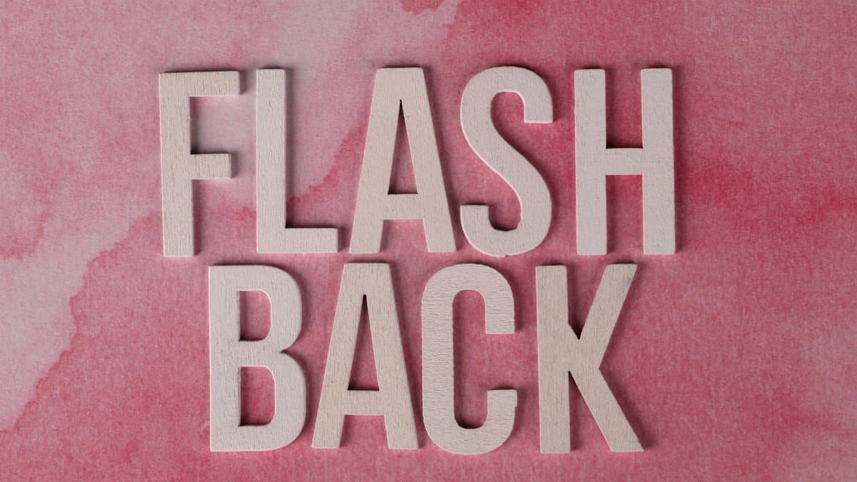 The word 'Flashback' in wooden letters on a pink watercolor background, creating a nostalgic theme.