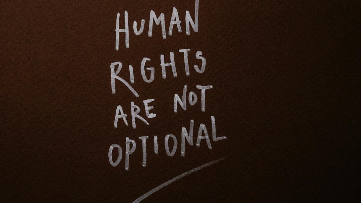 Handwritten message advocating for human rights on a rich brown background.