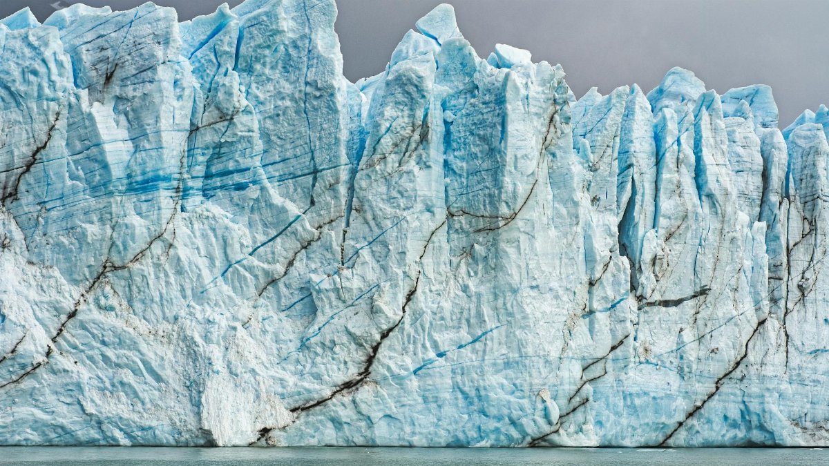Breathtaking view of a massive glacier with dramatic ice formations and cracks under overcast skies.