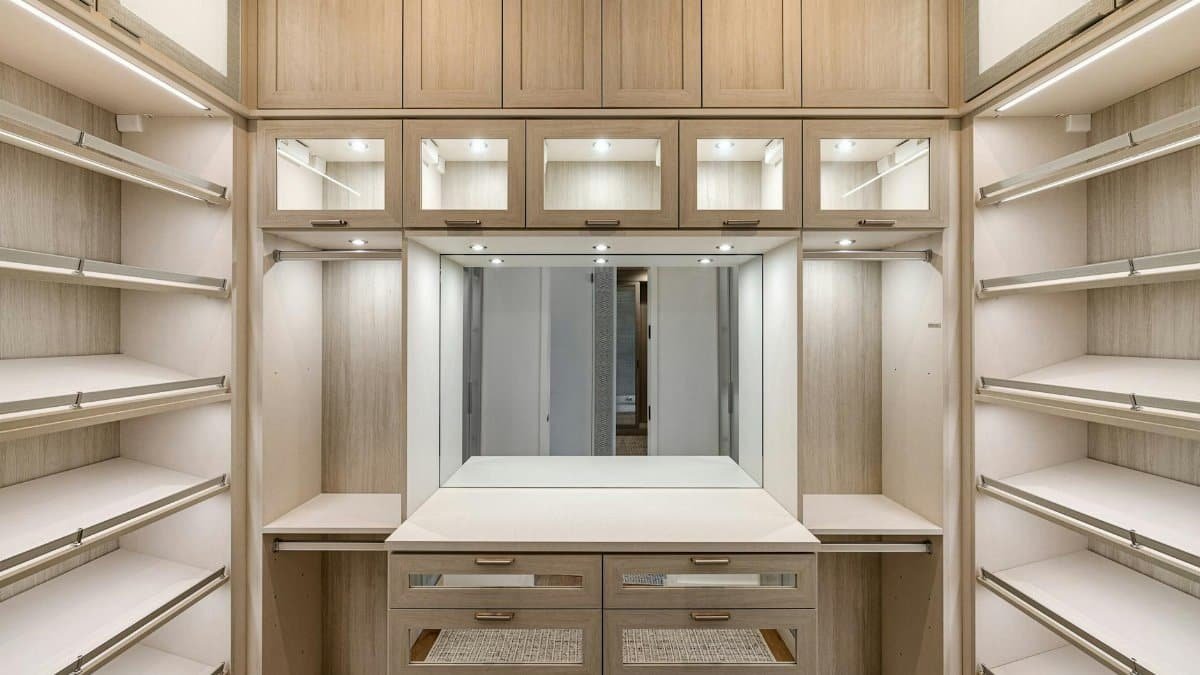 Spacious walk-in closet with wooden cabinets and ample lighting.