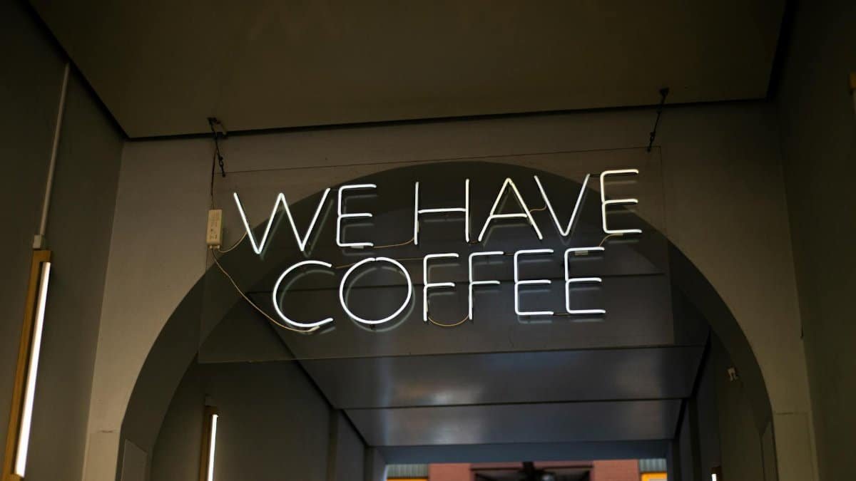 Neon sign reading 'We Have Coffee' at a coffee shop entrance in Berlin.