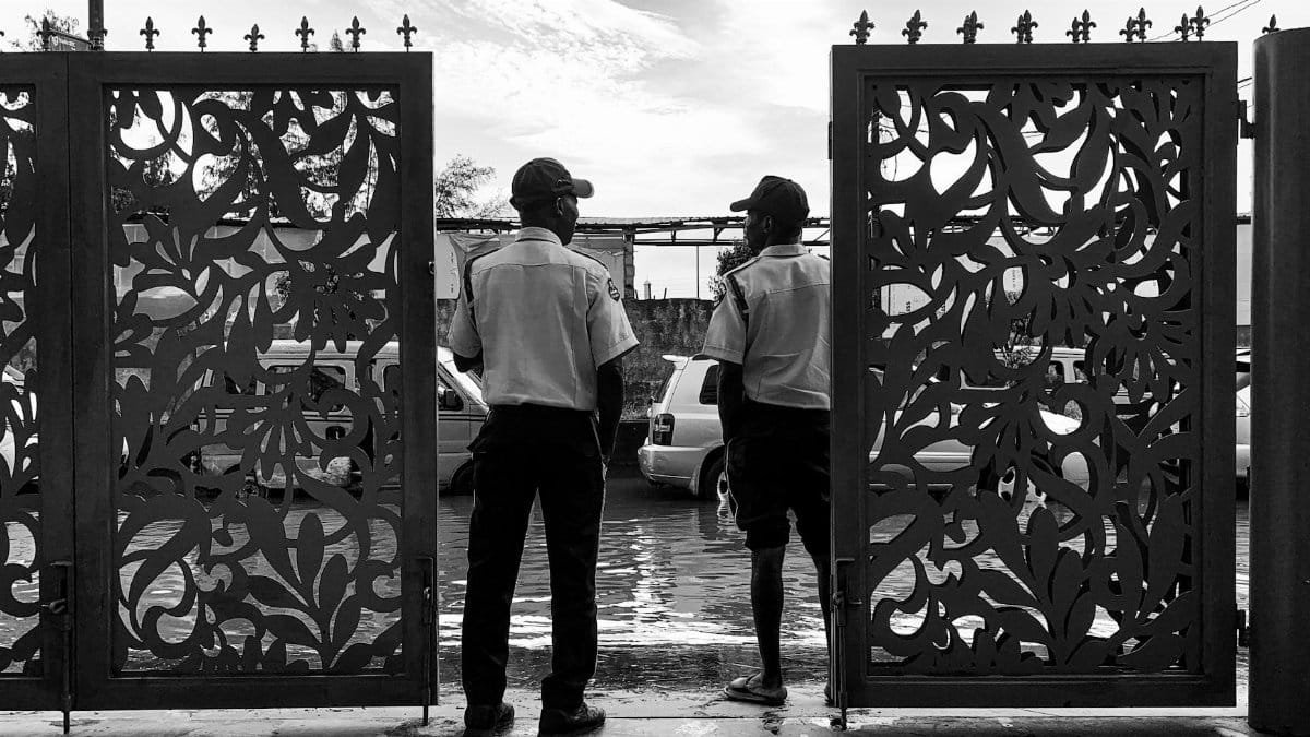 Black and white photo of two security guards standing by a decorative gate.