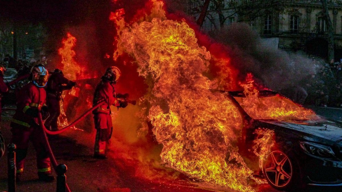 Intense photo of firefighters extinguishing a blazing car fire on the streets of Paris.