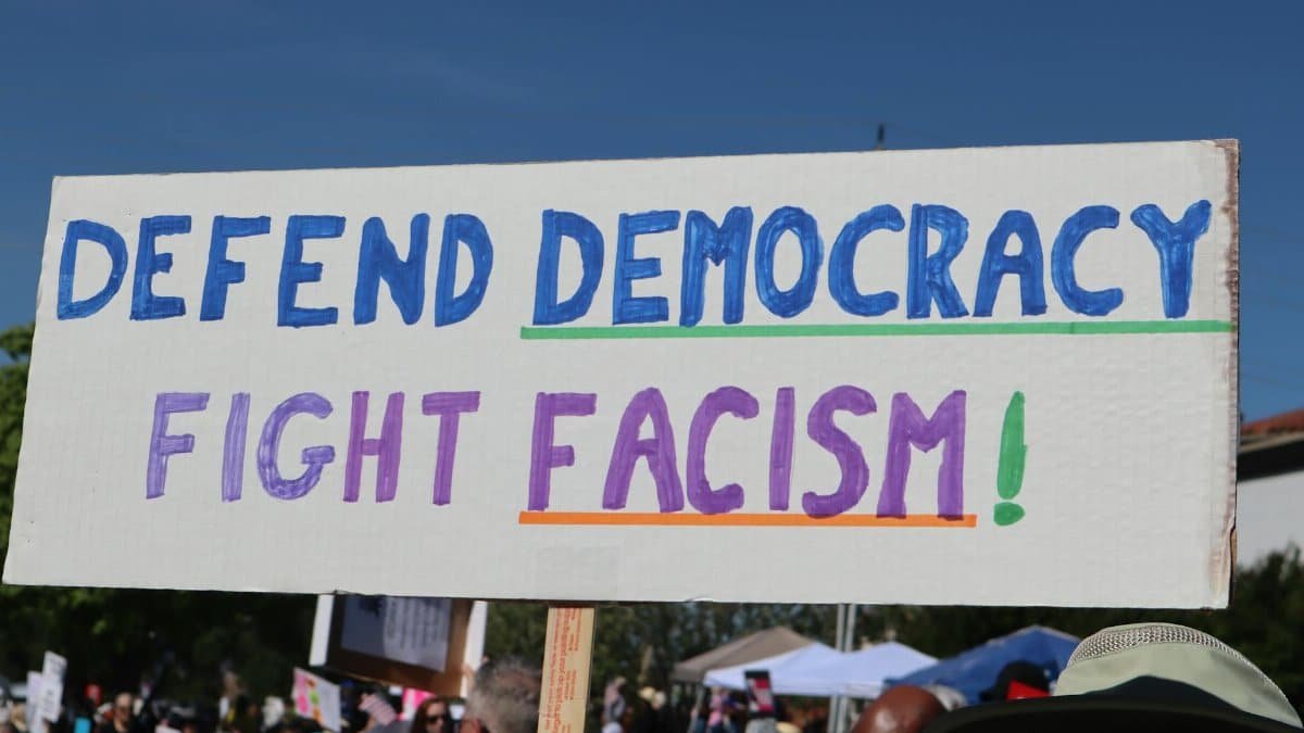 Protest sign reading 'Defend Democracy, Fight Fascism' at an outdoor rally in Elk Grove, CA.
