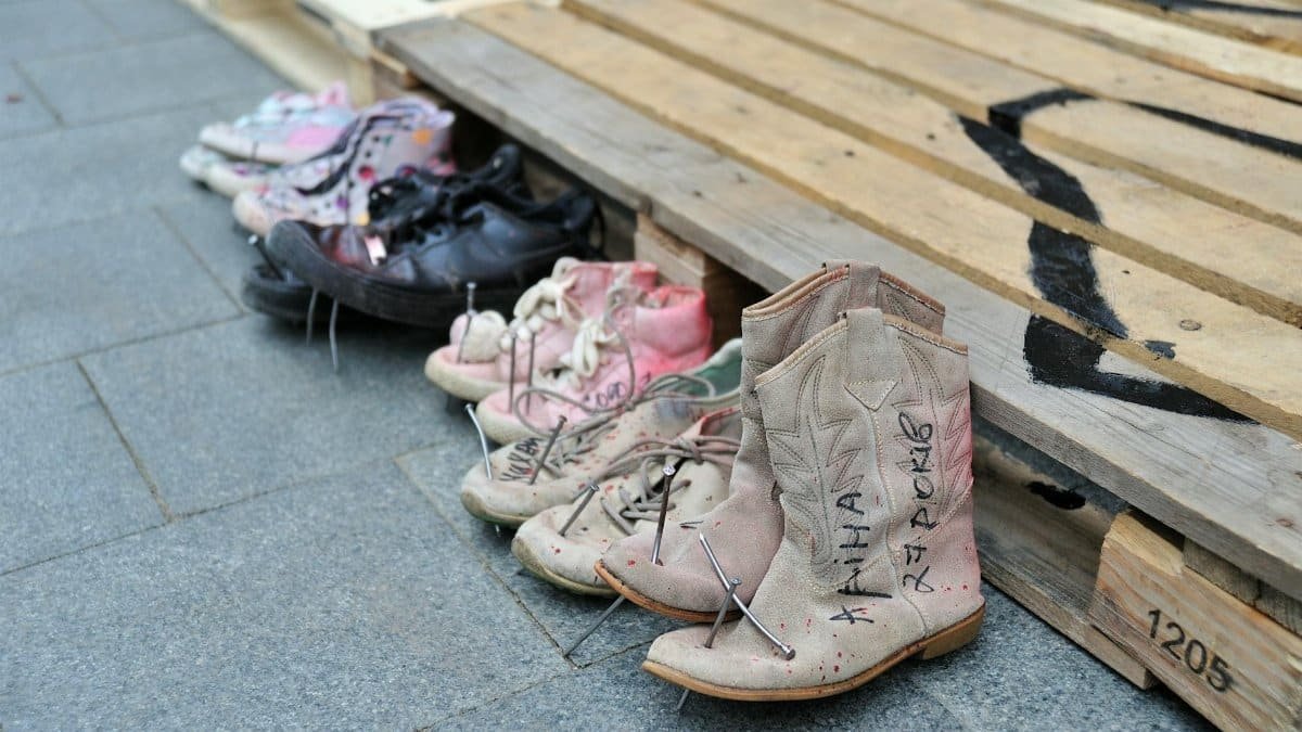 Display of various shoes on a wooden pallet in Lviv, Ukraine, symbolizing memorial.