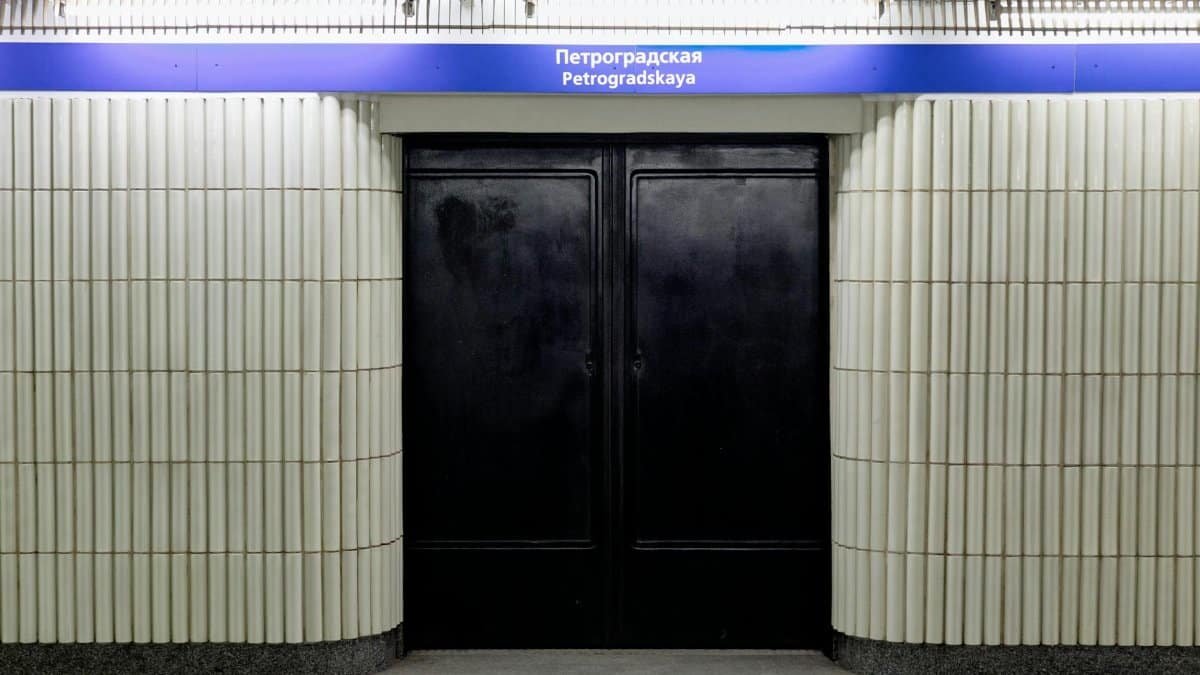 Entrance to Petrogradskaya Metro Station with ribbed white walls and black doors.