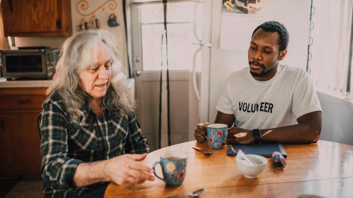 Two people sharing coffee and conversation in a cozy kitchen setting.