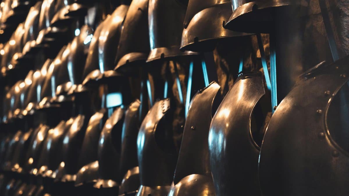 A collection of medieval knight helmets on display in a London museum, showcasing historical armor.