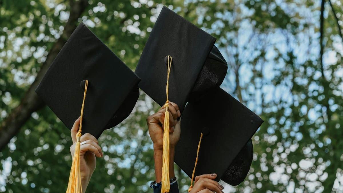 Three hands holding graduation caps in celebration, symbolizing success.