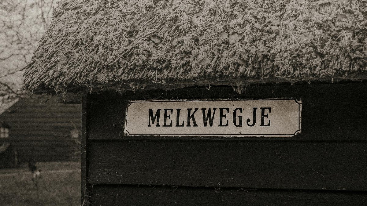 A rustic thatched roof with a Melkwegje street sign, evoking old town charm.