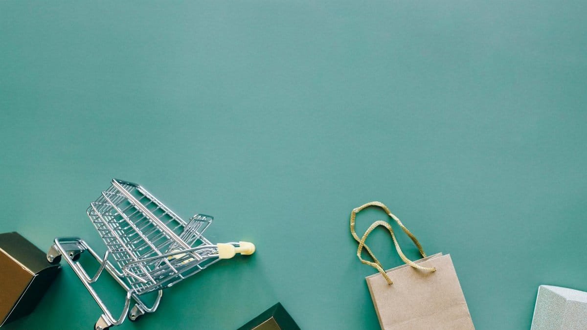 Top view of a shopping cart and bag on a blue background, ideal for retail themes.