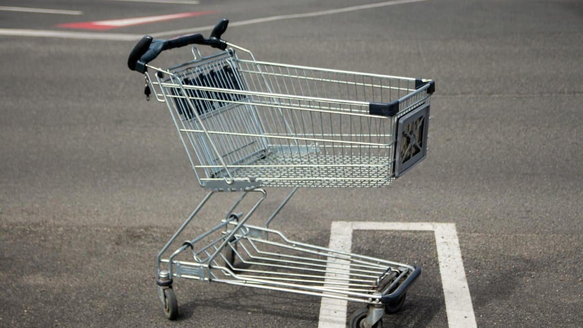 A lone shopping cart sits idle in an empty parking lot on a sunny day.