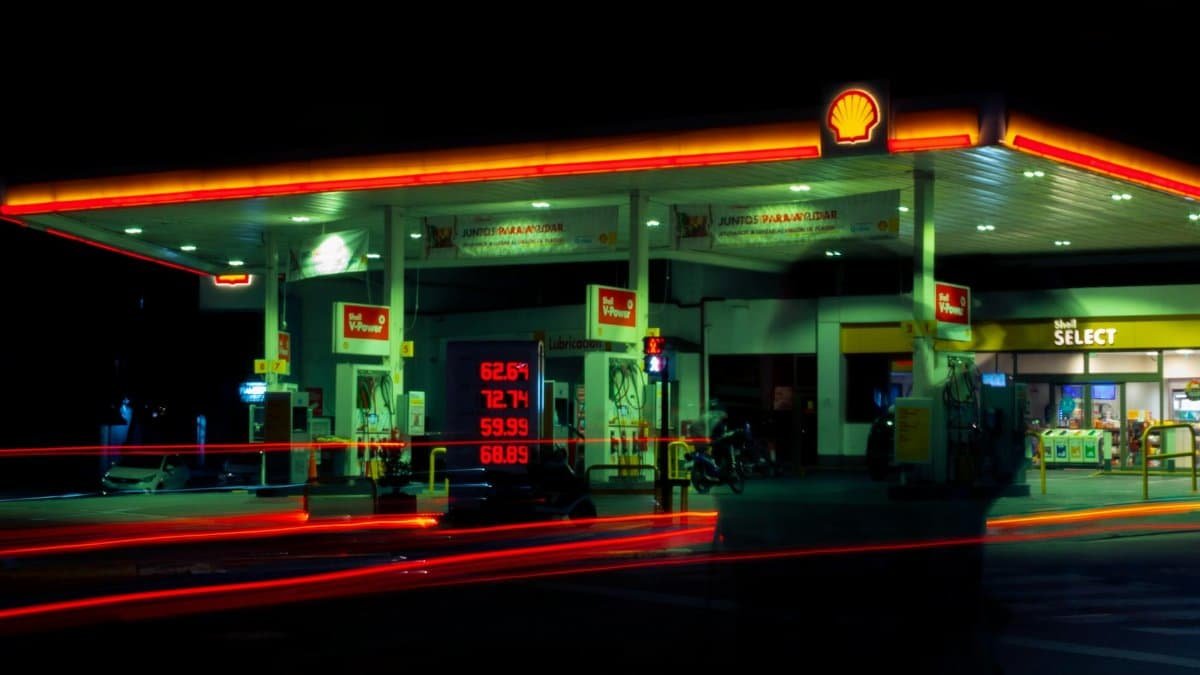 Illuminated Shell gas station with long exposure light trails at night.