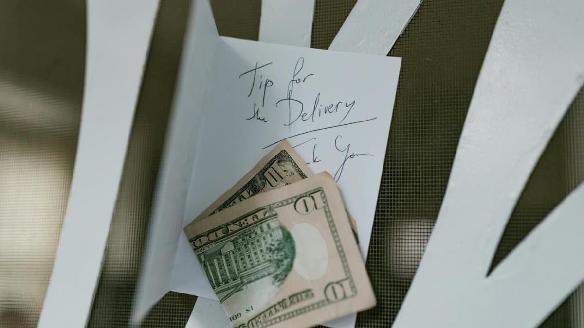 A photo of US dollar bills placed with a handwritten tip note for delivery service.