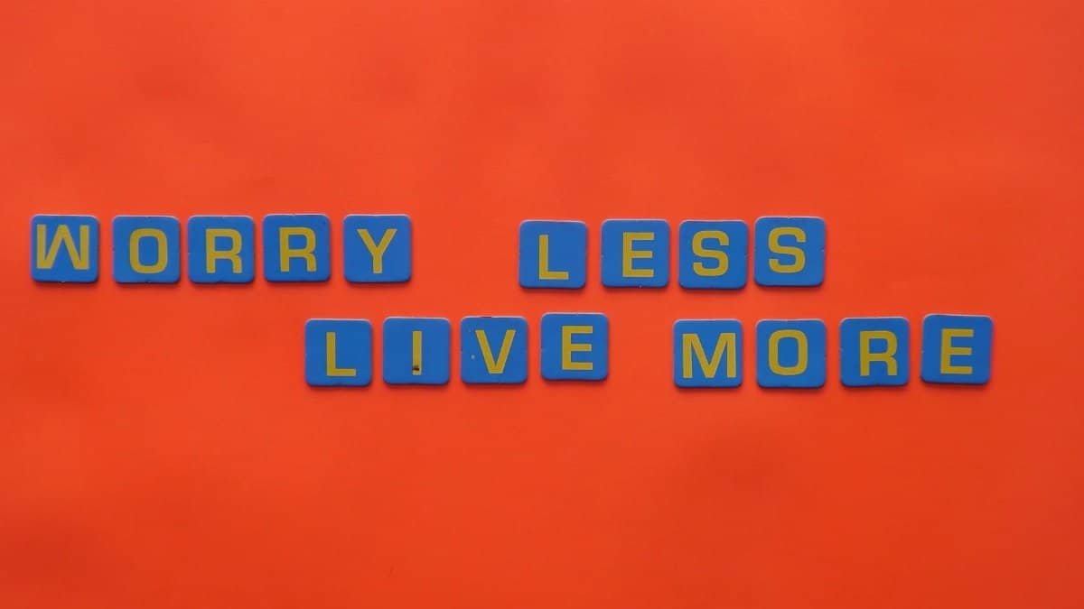 Blue tiles spelling 'Worry Less Live More' on an orange background for a motivational theme.