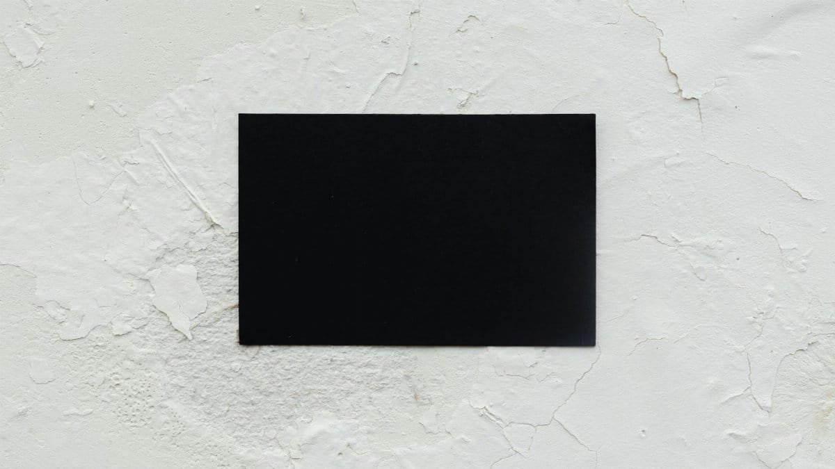 A blank black business card placed on a rough white textured surface, ideal for mockup use.