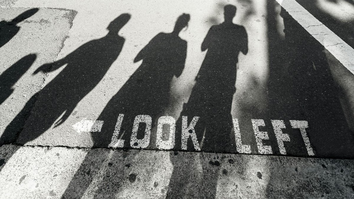 Shadows of pedestrians cast on crosswalk with 'Look Left' sign in Sydney.